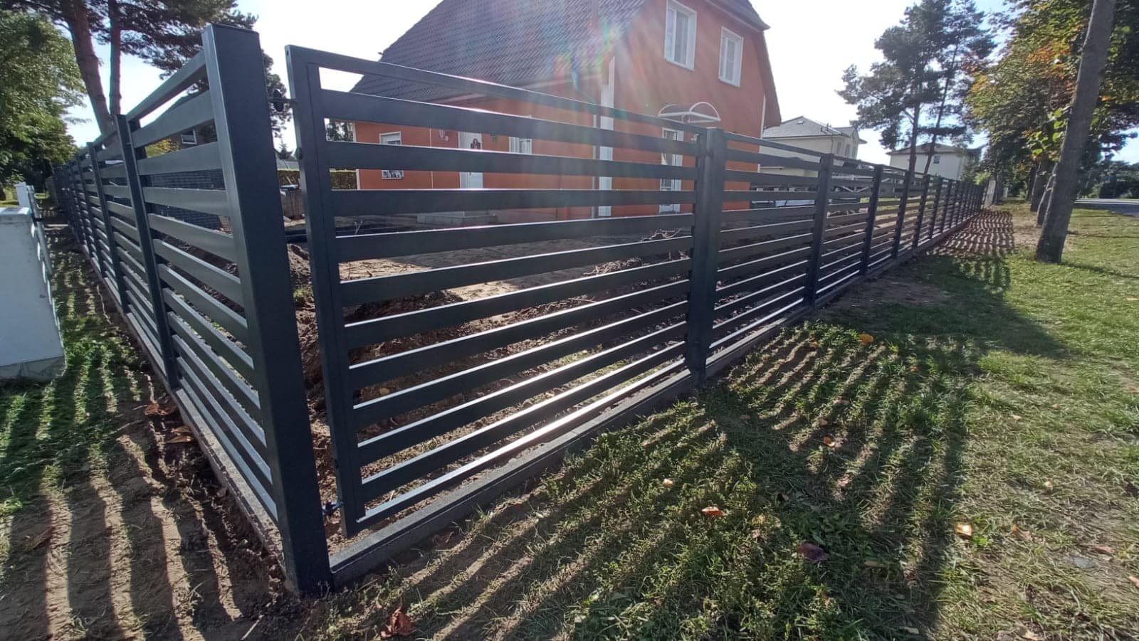 Dekorativer Zaun aus Edelstahlpaneelen in Graphit. Die Paneele weisen ein Muster aus geometrischen Formen auf.